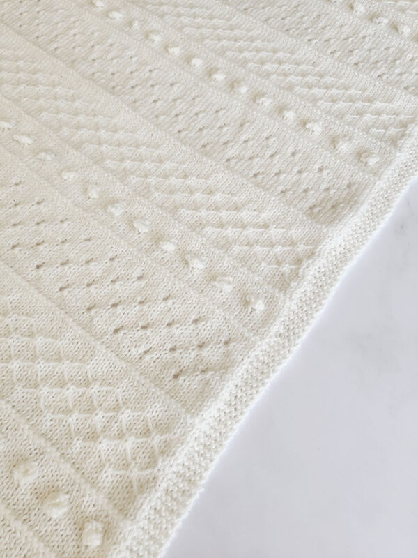 Unisex knitted baby blanket with textured knit stitches made with DK yarn