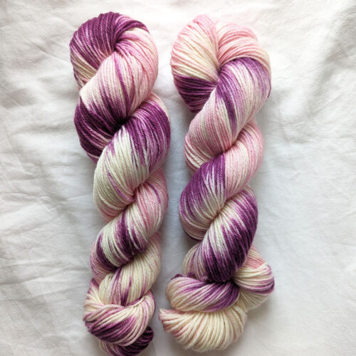 Tow skeins of hand painted purple, pink and natural DK yarn