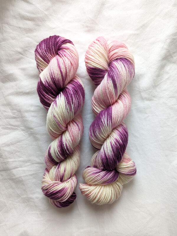 Tow skeins of hand painted purple, pink and natural DK yarn