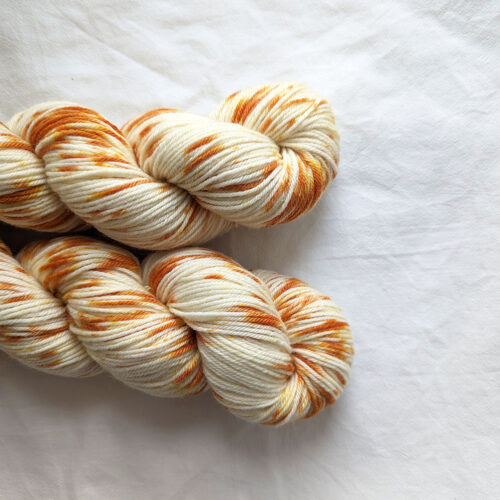 Two skeins of hand painted dk yarn with golden orange splashes