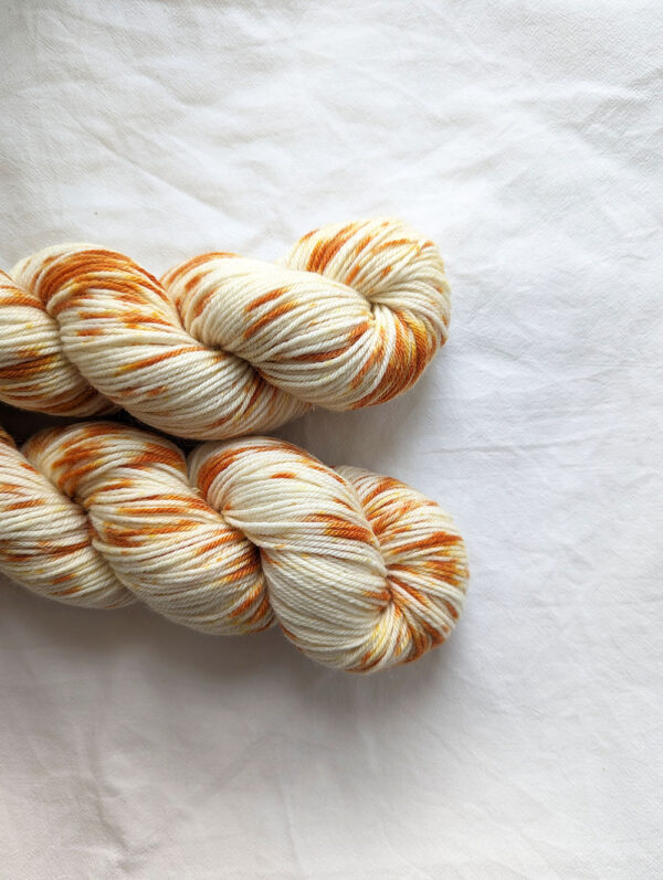 Two skeins of hand painted dk yarn with golden orange splashes