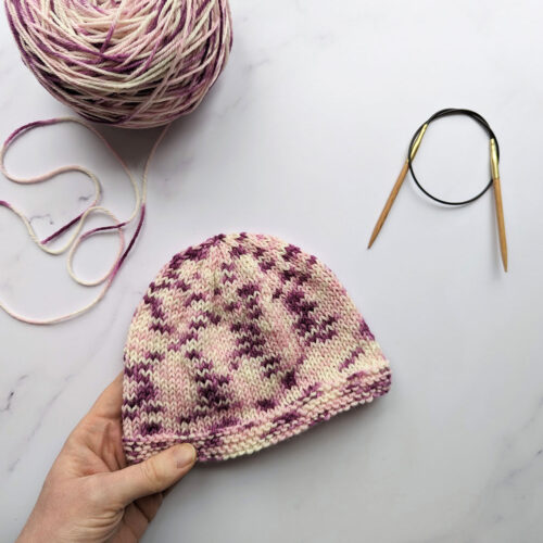 simple baby hat made from purple and pink hand dyed yarn from a beginners knitting kit