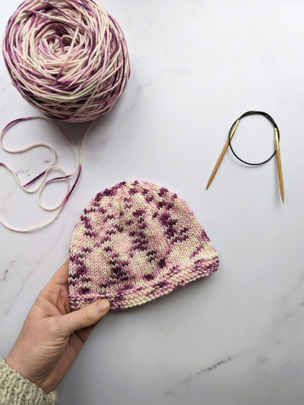 simple baby hat made from purple and pink hand dyed yarn from a beginners knitting kit