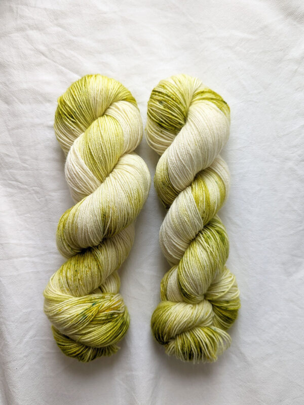 Two skeins of speckled olive green fingering weight yarn