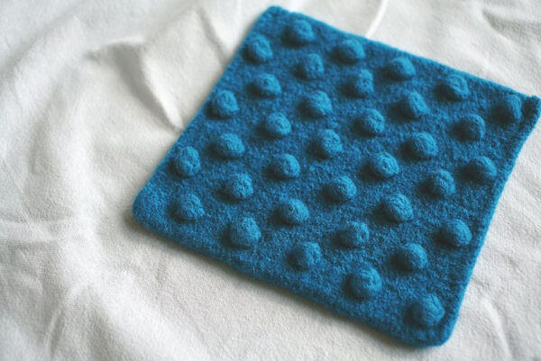 Knitted and felted wool potholder in teal with bobbles