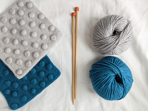 Felted potholder knitting kit contents with straight needles and teal or grey yarn