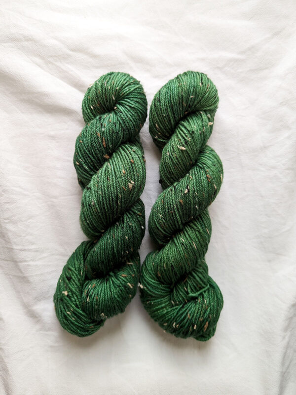 Two skeins of forest green hand dyed yarn with tweed specks